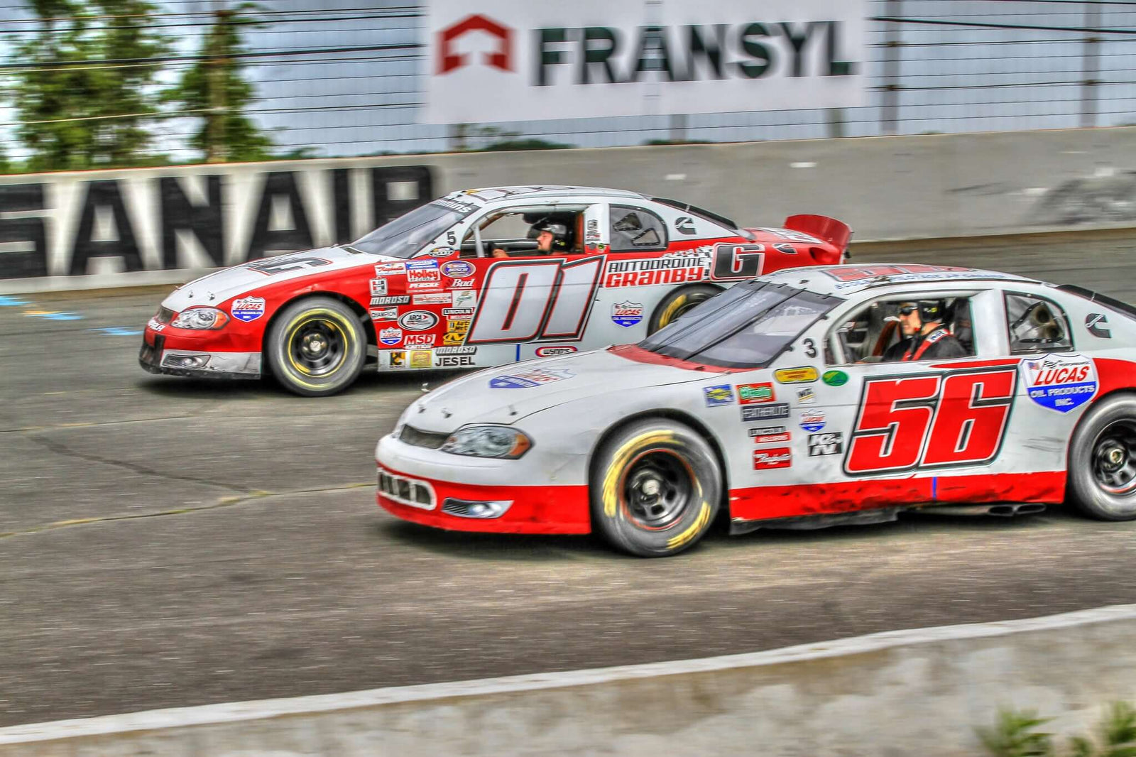 Deux voitures de course NASCAR sur le circuit SANAIR, en pleine compétition lors d'une expérience de conduite.